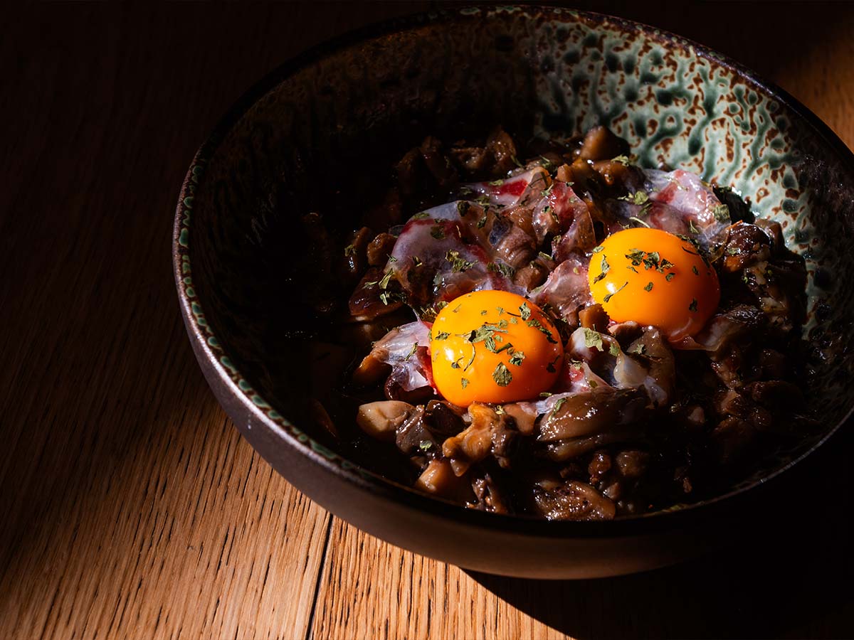 Salteado de setas silvestres con yema de huevo, papada ibérica de Maldones y aceite de trufa