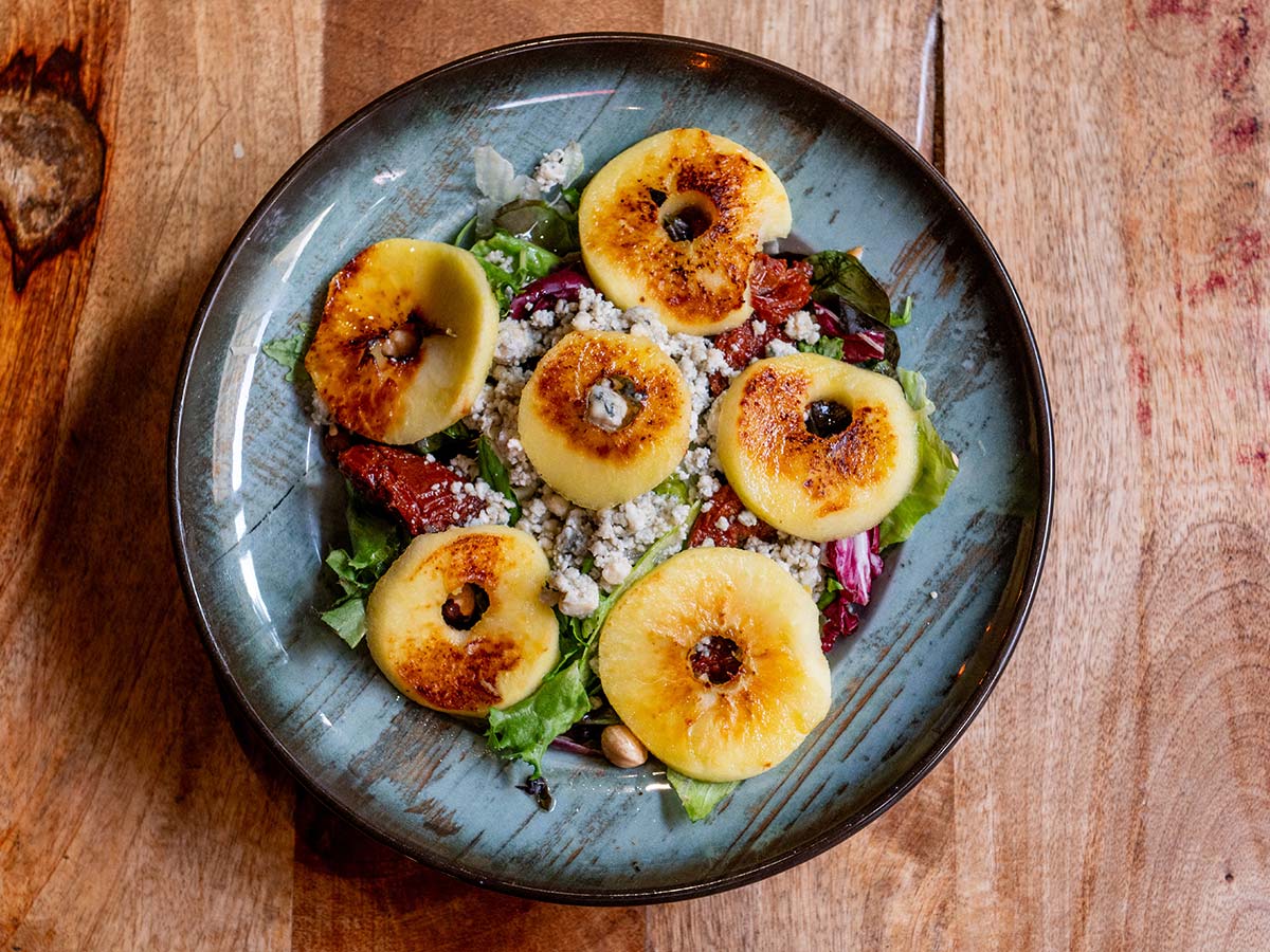Ensalada templada de queso azul, tomate seco, frutos secos, manzana y miel